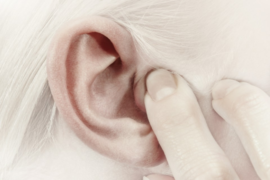 kobieta trzyma palec na uchu